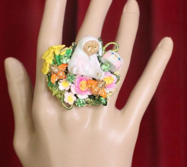 A hand wearing a ring with flowers and a person