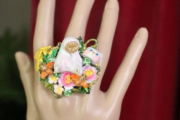 A hand wearing a ring with flowers on it