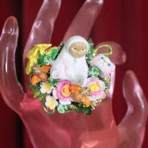 A hand with a ring on it and some flowers around the finger.