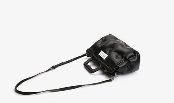 A black purse is laying on the ground.