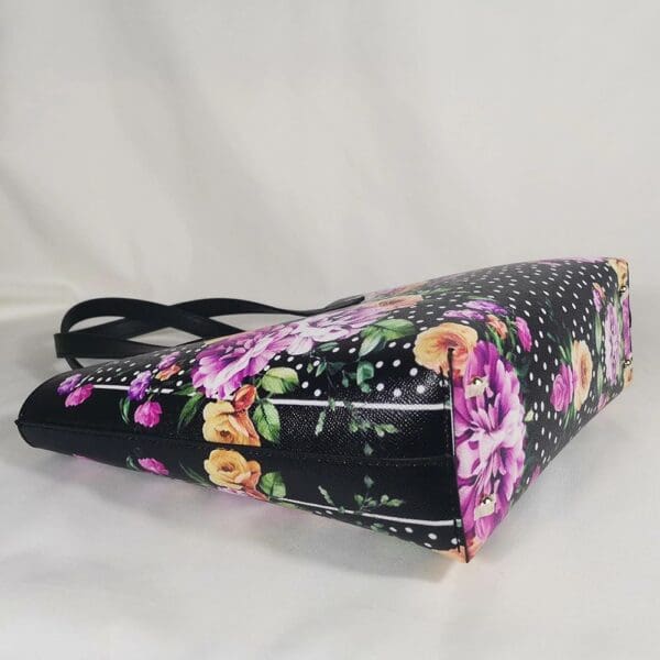 A black purse with purple flowers on it.