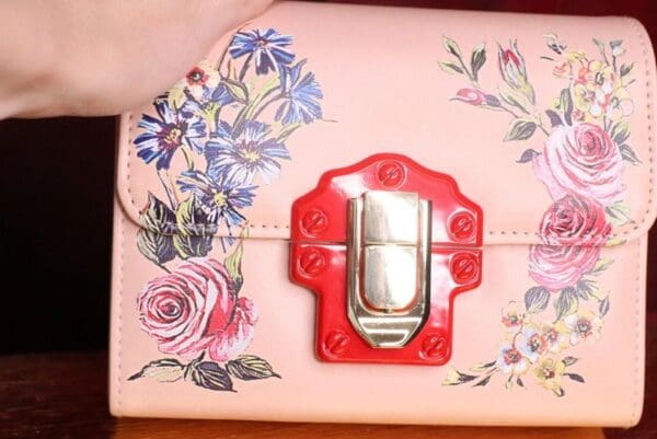 A close up of the red buckle on a pink purse