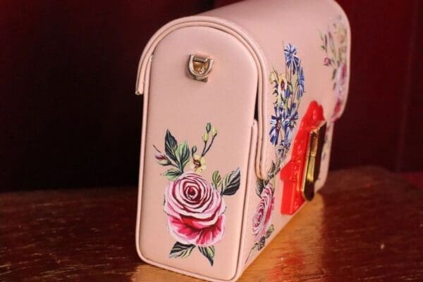 A pink mailbox with flowers painted on it.