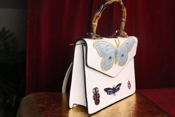 A white purse with blue and yellow butterflies on it.