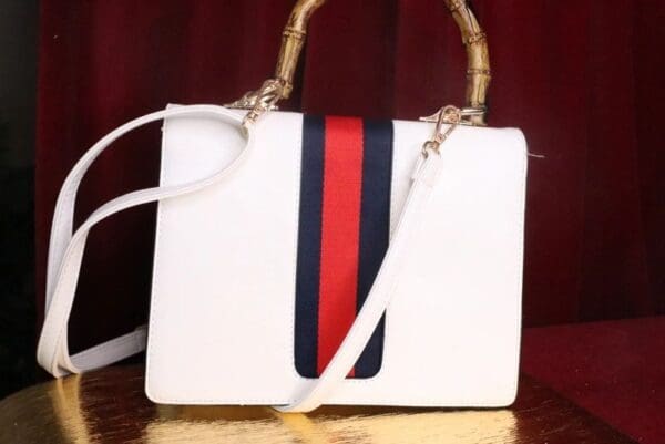 A white purse with red and blue stripes on it.