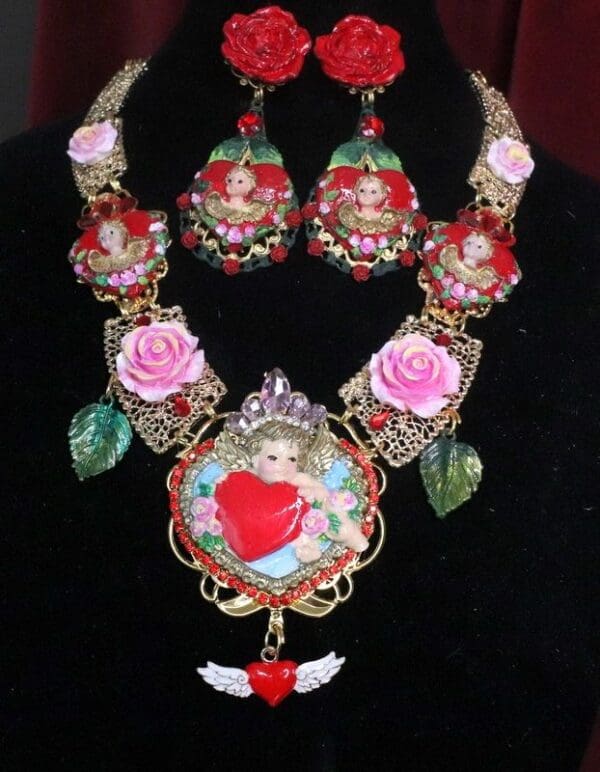 A necklace and earrings set with pink roses, angel and heart.