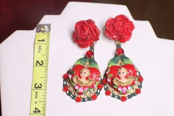 A pair of earrings with red roses and a large picture