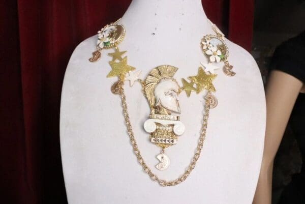 A white mannequin wearing a necklace with gold chains and charms.