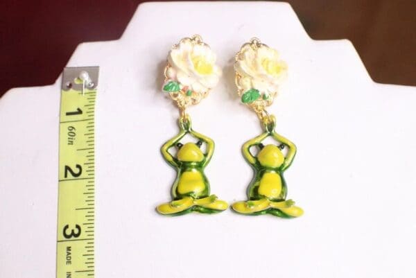 A pair of earrings with a frog sitting on top of it.