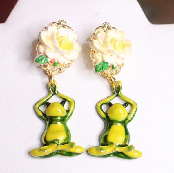 A pair of earrings with yellow flowers and green frog.