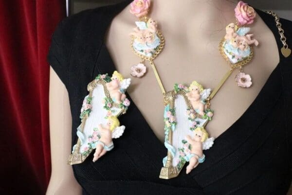 A woman wearing a necklace and earrings with cherubs.