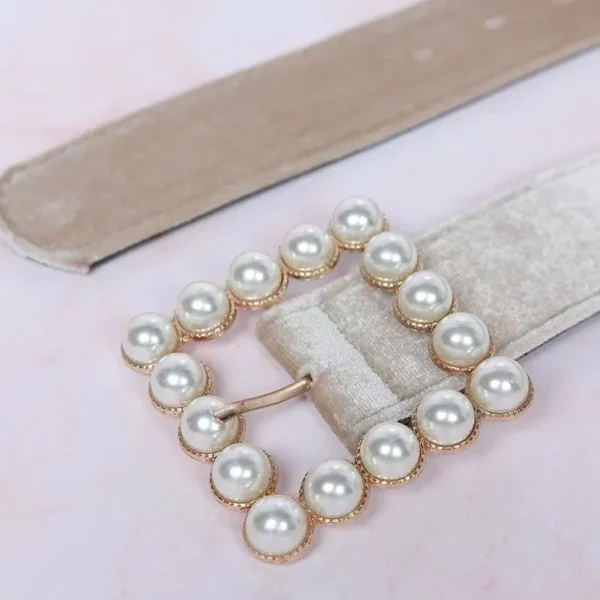 A close up of the belt buckle on a white belt