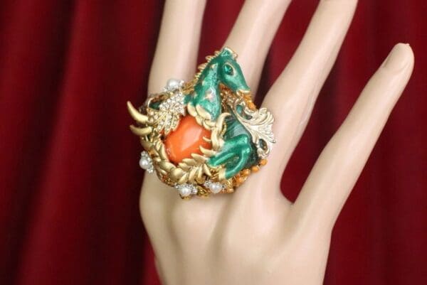 A hand wearing a ring with a horse on it