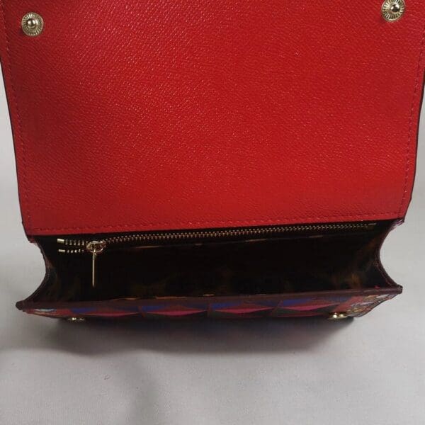 A red purse with a black and gold handle.
