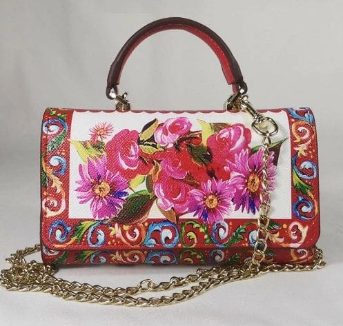 A purse with flowers on it and chain strap.