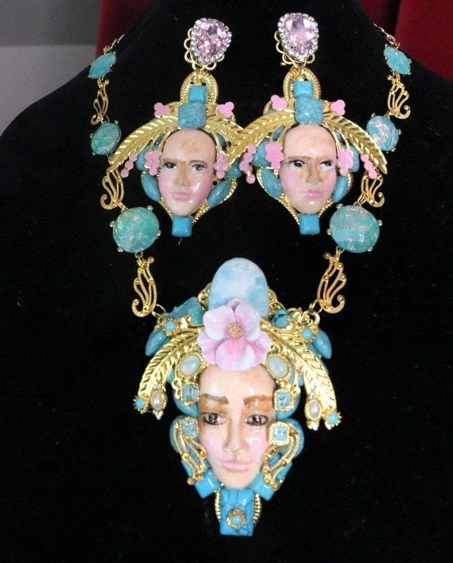 A necklace and earrings set with faces of women.