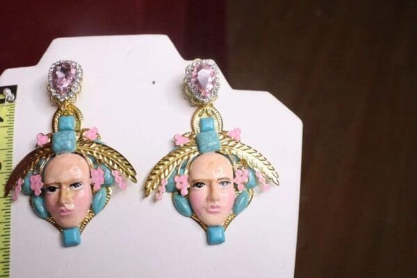 A pair of earrings with faces and flowers on them.