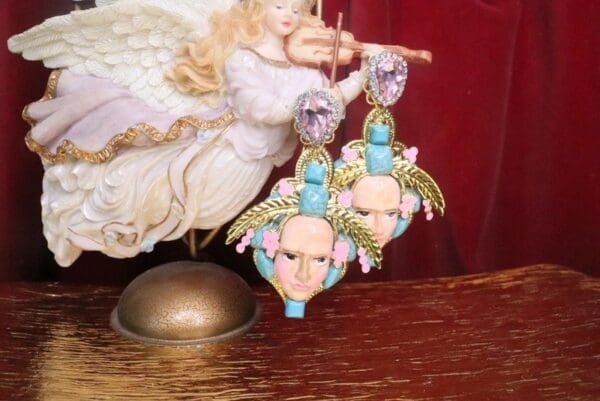 A pair of earrings with faces and flowers on them.