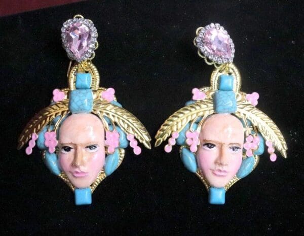 A pair of earrings with faces and flowers on them.