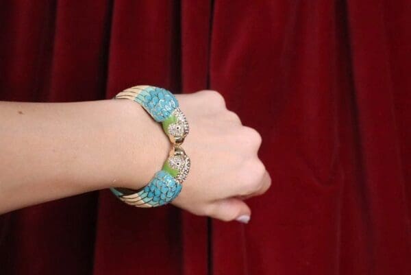 A woman 's hand wearing a bracelet with blue and white beads.