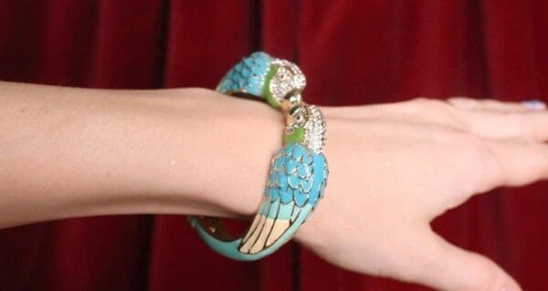 A woman 's arm with a blue and green bracelet on it.