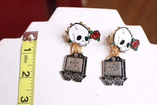 A pair of earrings with skulls and roses on them.