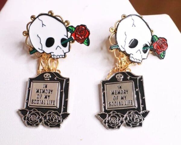A pair of skull earrings with roses on them.