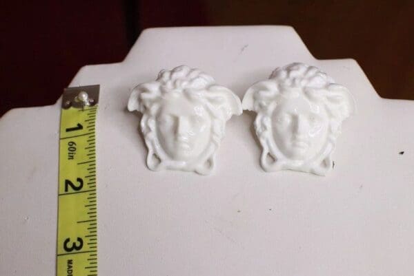 A pair of white earrings with faces on them.