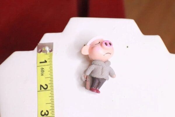 A small toy is shown next to a ruler.