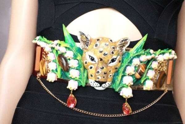 A woman wearing a leopard head and green leaves on her belt.