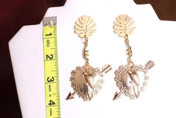 A pair of earrings with a ruler and a leaf