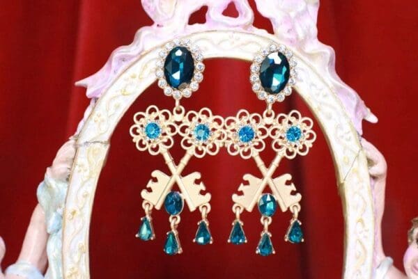 A pair of earrings with blue stones hanging from them.
