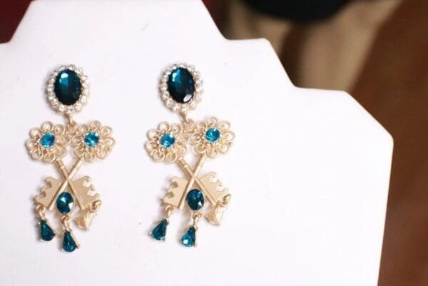 A pair of earrings with blue stones on top of a white card.