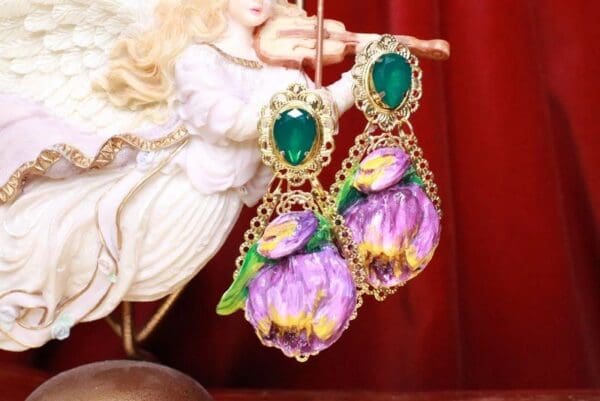 A pair of earrings with flowers and green stones.