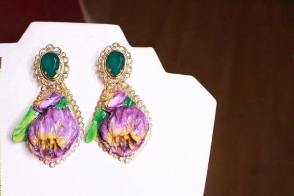 A pair of earrings with purple flowers on them.