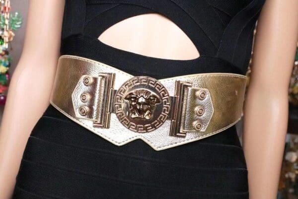 A woman wearing a black dress and gold belt.