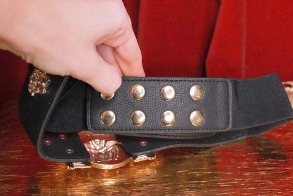 A person holding onto the strap of a black purse.