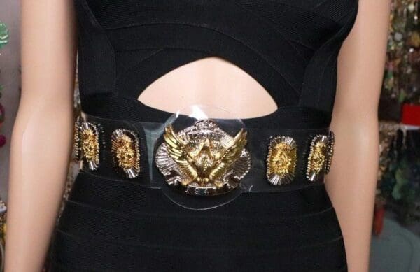 A woman wearing a black dress and belt with gold embellishments.