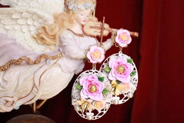 A statue of an angel with pink flowers on them.