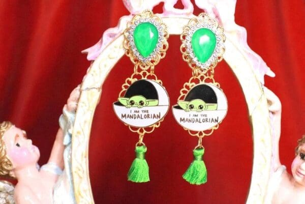 A pair of earrings with green tassels and a picture.