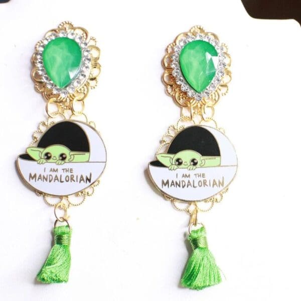 A pair of earrings with green tassels and a picture.