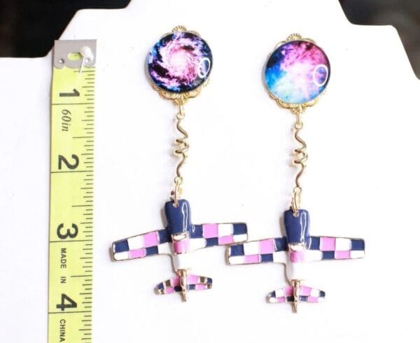 A pair of earrings with a plane and space background.