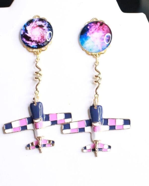 A pair of earrings with a plane and space background.