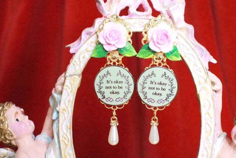 A pair of earrings with pink roses and pearls.