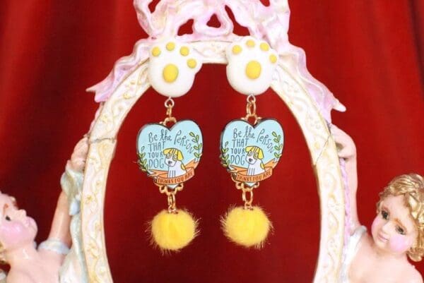 A pair of earrings with yellow fur and blue heart.