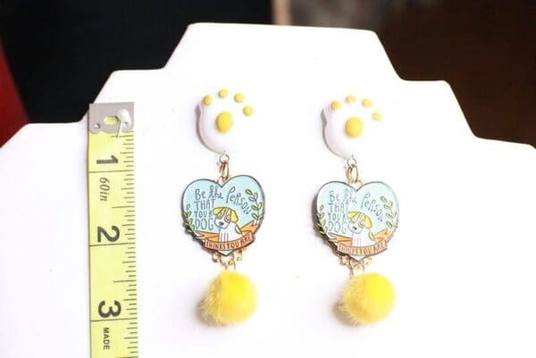 A pair of earrings with yellow and white fur on them.