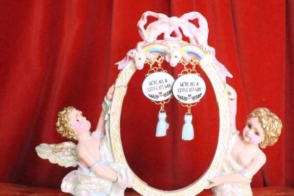 A pair of earrings hanging from the side of a mirror.