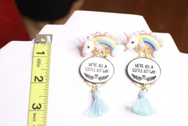 A pair of earrings with a unicorn and rainbow on them.
