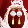 A pair of earrings with yellow tassels and a crown.