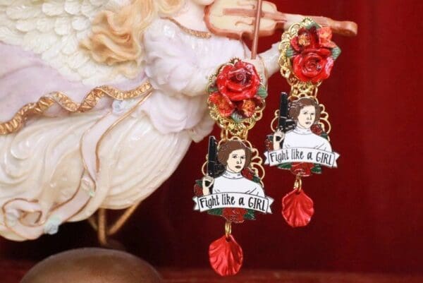 A pair of earrings with red roses and a woman 's face.